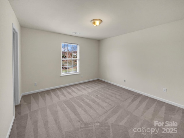 carpeted spare room featuring visible vents and baseboards