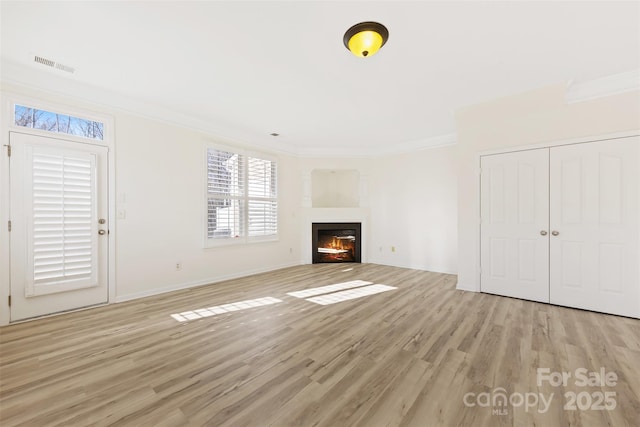 unfurnished living room featuring crown molding, light wood-type flooring, visible vents, and a lit fireplace