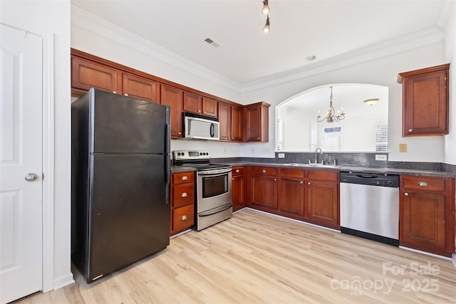 kitchen featuring visible vents, a sink, ornamental molding, stainless steel appliances, and dark countertops