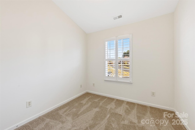 carpeted empty room with visible vents, baseboards, and lofted ceiling