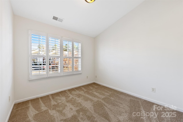 spare room with carpet flooring, visible vents, baseboards, and lofted ceiling