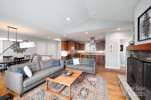 living room with lofted ceiling, light wood-style flooring, recessed lighting, a fireplace, and baseboards