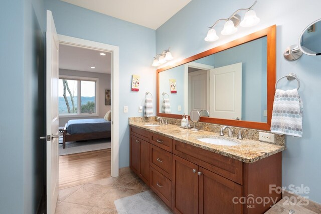 ensuite bathroom featuring a sink, ensuite bathroom, double vanity, and tile patterned flooring