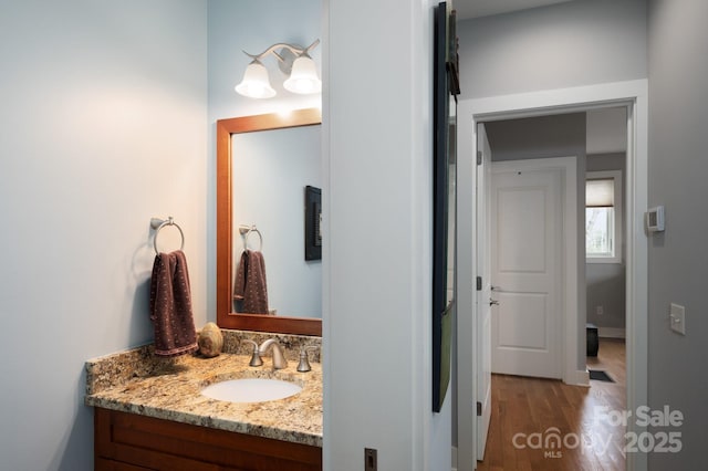 bathroom with vanity, wood finished floors, and baseboards