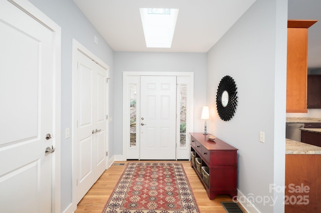 entryway with a skylight, light wood-style floors, visible vents, and baseboards