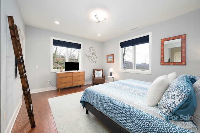 bedroom with recessed lighting, multiple windows, baseboards, and wood finished floors