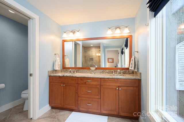 bathroom with a sink, toilet, a stall shower, and double vanity