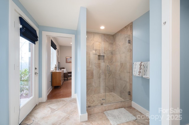 ensuite bathroom featuring plenty of natural light, a stall shower, ensuite bathroom, and baseboards