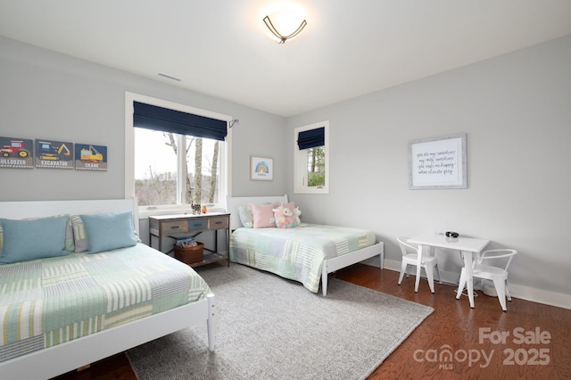 bedroom featuring visible vents, multiple windows, baseboards, and wood finished floors