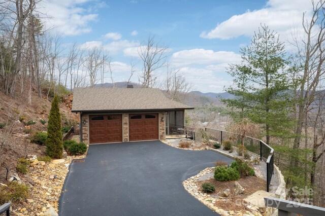 garage with a mountain view, driveway, and fence