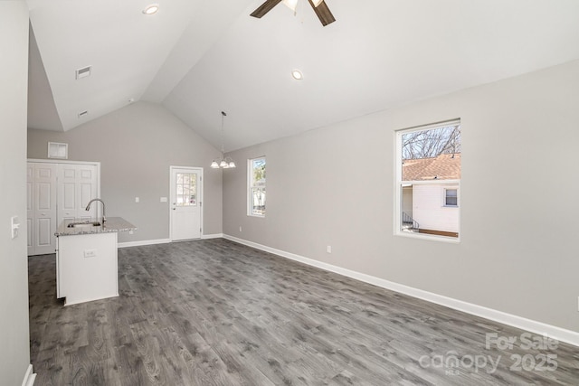 unfurnished living room with visible vents, a sink, dark wood-style floors, baseboards, and vaulted ceiling