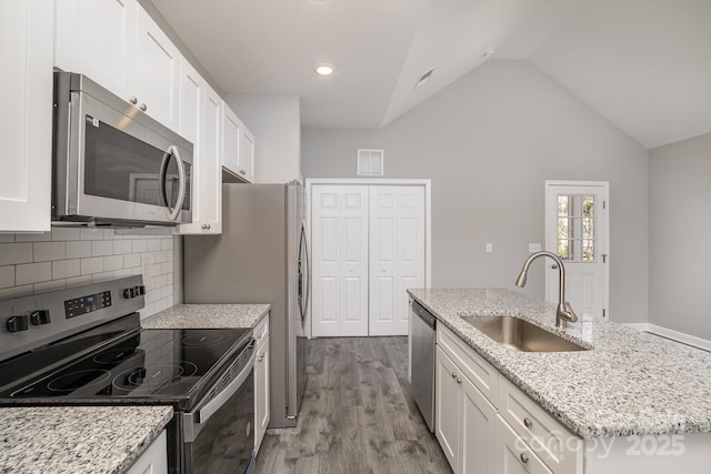 kitchen featuring white cabinets, wood finished floors, appliances with stainless steel finishes, and a sink