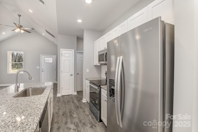 kitchen with light stone countertops, dark wood-style flooring, a sink, stainless steel appliances, and white cabinets