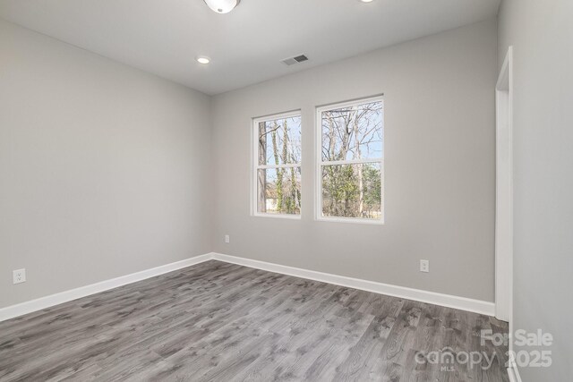 spare room with recessed lighting, visible vents, baseboards, and wood finished floors