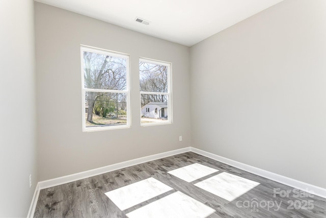 spare room with visible vents, baseboards, and wood finished floors