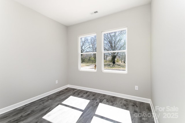 unfurnished room featuring dark wood-style floors, baseboards, and visible vents