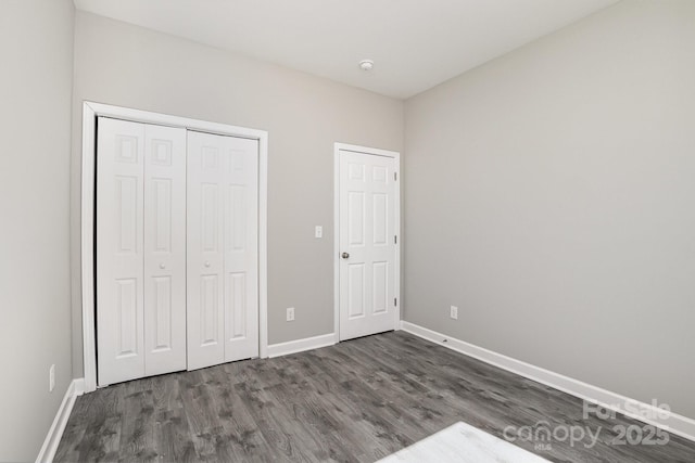 unfurnished bedroom featuring a closet, baseboards, and wood finished floors