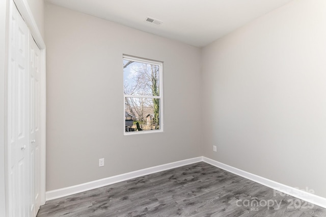 unfurnished bedroom with a closet, visible vents, baseboards, and dark wood-style floors