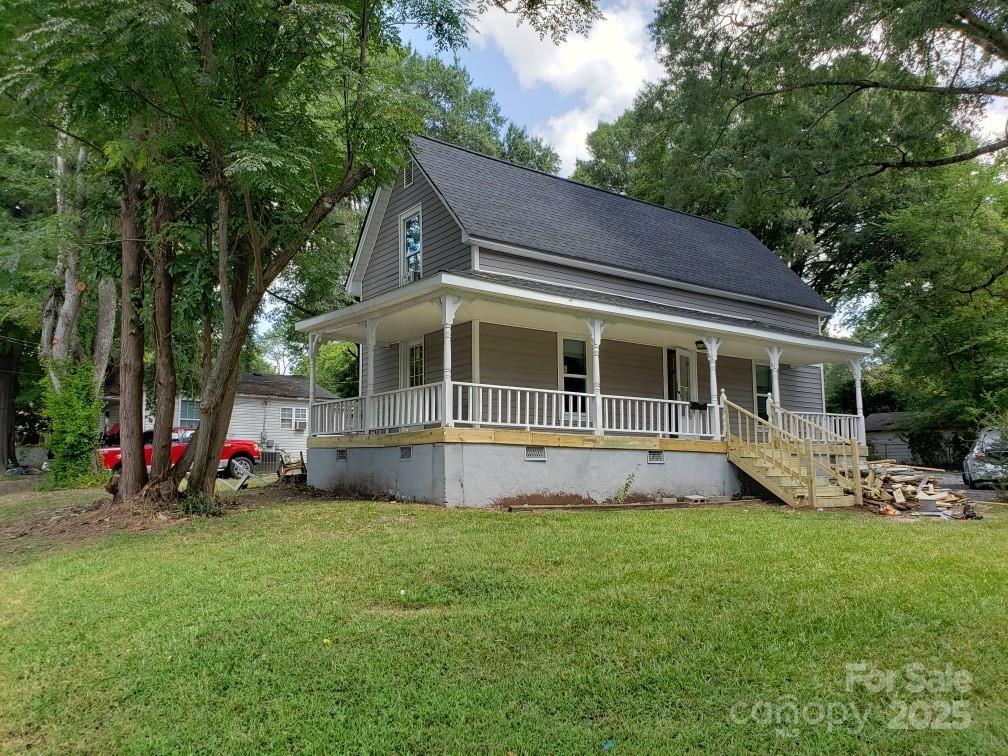 farmhouse inspired home with a porch, a front lawn, roof with shingles, and crawl space