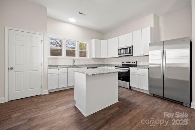 kitchen with appliances with stainless steel finishes, white cabinetry, and dark wood-type flooring