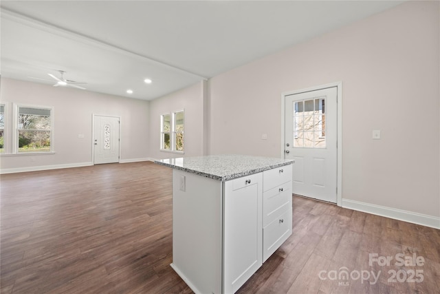 kitchen with a healthy amount of sunlight, wood finished floors, a center island, and white cabinets