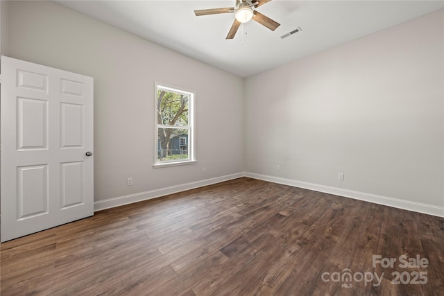 empty room featuring visible vents, baseboards, dark wood-style floors, and a ceiling fan