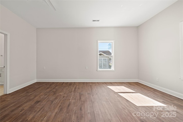 spare room featuring visible vents, baseboards, and wood finished floors