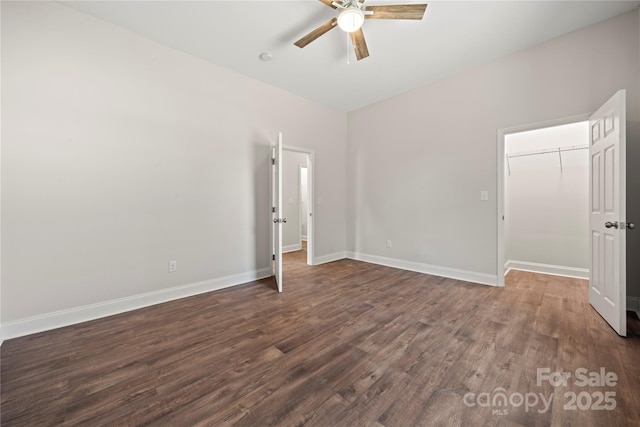 empty room featuring a ceiling fan, dark wood-style flooring, and baseboards