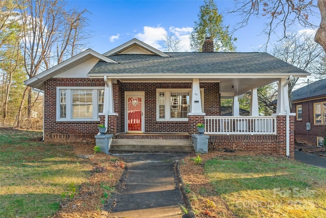 bungalow-style house with covered porch, brick siding, roof with shingles, and a chimney