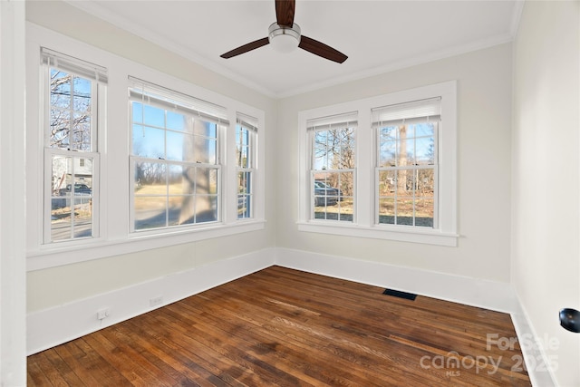 unfurnished room with dark wood-style floors, visible vents, crown molding, and a wealth of natural light