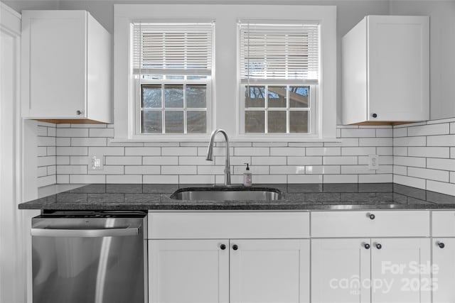 kitchen featuring stainless steel dishwasher, white cabinetry, backsplash, and a sink