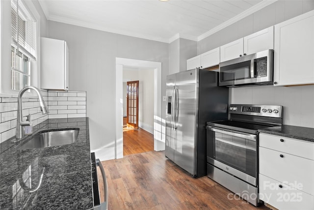 kitchen featuring dark wood-style flooring, a sink, ornamental molding, stainless steel appliances, and tasteful backsplash