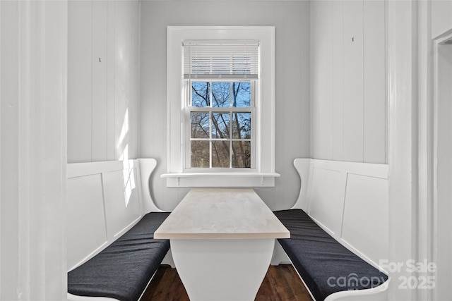 dining space featuring a decorative wall and dark wood-style flooring