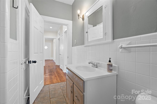 half bathroom with vanity, wainscoting, tile walls, toilet, and tile patterned floors