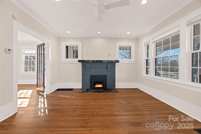 unfurnished living room featuring a brick fireplace, crown molding, baseboards, and wood finished floors