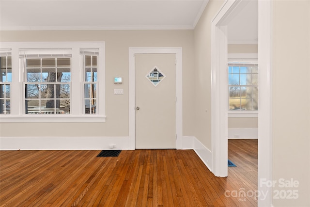 entrance foyer featuring baseboards, visible vents, wood-type flooring, and ornamental molding