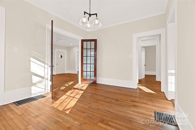 unfurnished dining area with visible vents, wood-type flooring, ornamental molding, and french doors