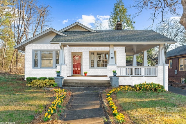 bungalow with brick siding, a chimney, and a front lawn