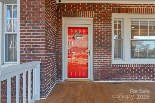 property entrance with brick siding and visible vents