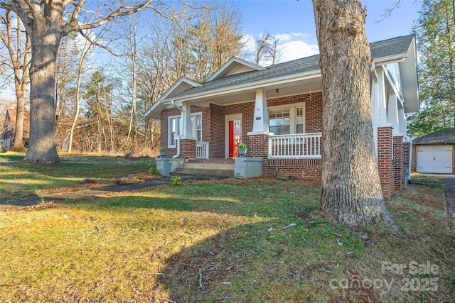 view of front of house with brick siding, covered porch, a shingled roof, and a front yard