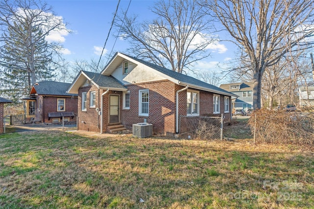 view of front of property with brick siding, a front lawn, entry steps, central AC, and roof with shingles