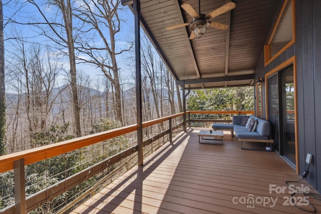 wooden deck featuring a forest view and ceiling fan