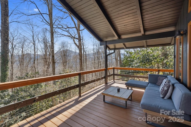 deck with an outdoor living space and a wooded view