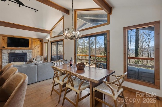 dining space featuring lofted ceiling with beams, light wood finished floors, and a chandelier