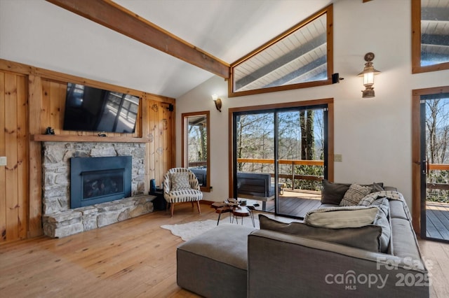 living room featuring wood-type flooring, a fireplace, and vaulted ceiling with beams