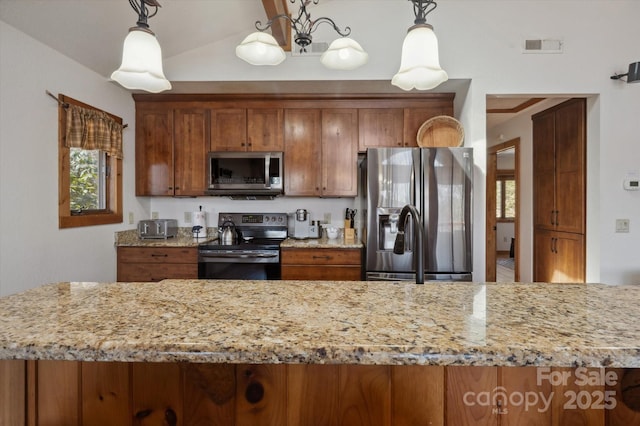 kitchen featuring brown cabinets, appliances with stainless steel finishes, and light stone countertops