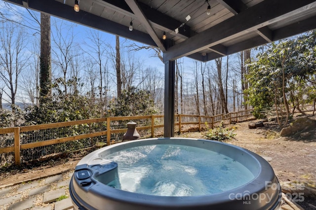 view of pool with fence and a hot tub