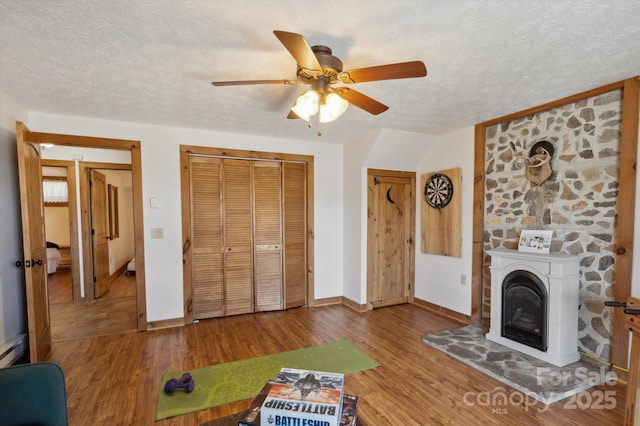 unfurnished living room with a fireplace, wood finished floors, baseboards, and a textured ceiling