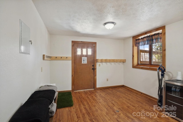 foyer featuring wood finished floors, baseboards, and a textured ceiling