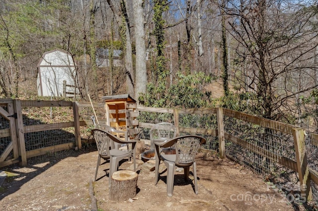 view of patio featuring a storage shed, an outbuilding, fence, and a view of trees